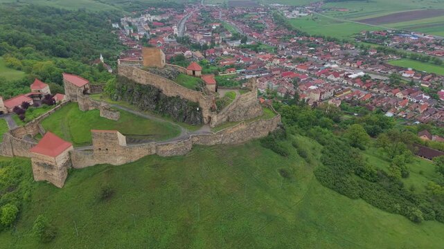 Stunning aerial footage of the Rupea Citadel, a medieval fortress in Transylvania, Romania, perched atop a hill overlooking the town