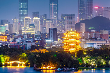 Fototapeta premium Illuminated traditional pavilion in modern city skyline at night