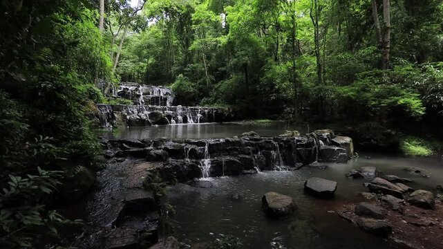 The video background features a natural landscape of a waterfall in a large forest. Sam Lan Waterfall in Saraburi National Park has beautiful flowing water.