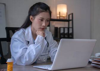 Asian female doctor using laptop working late at medical office desk © Alisa siangjam
