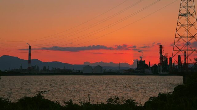 大野川越しに広がる大分臨海工業地帯のシルエットと沈みゆく夕日のタイムラプス（大分県）