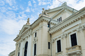 Obraz premium Classical theater building facade with statues and ornate architecture Description: Low angle architectural shot of an elegant national theater or opera house featuring classical columns, beautiful sc