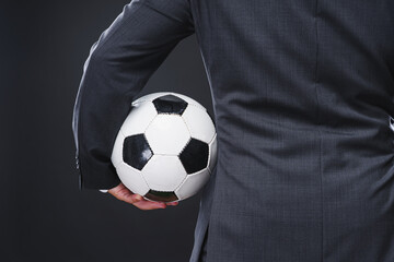Naklejka premium a sporty man in an elegant suit with the soccer ball - coach or professional player concept