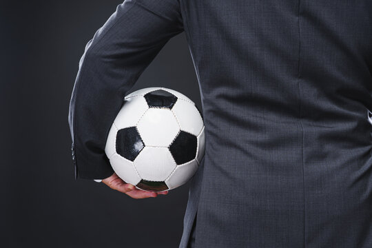 a sporty man in an elegant suit with the soccer ball - coach or professional player concept