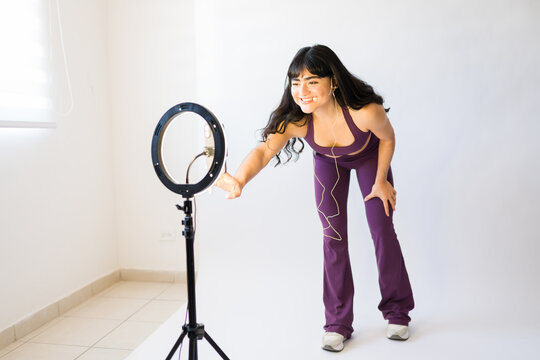 Active woman leading online fitness class from home, making video content for virtual workout and health streaming