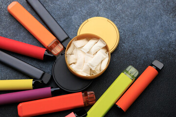 Various nicotine pouches and electronic cigarettes on a flat surface with colorful designs © ir1ska