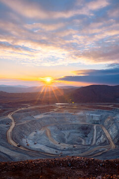 Majestic Sunrise Over a Vast Open-Pit Mine with Winding Roads and Dramatic Skies