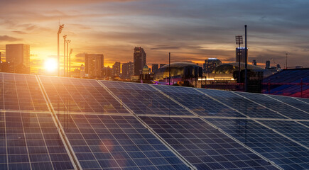 Solar panels in a modern city at sunset highlighting clean energy and urban sustainability. © banphote