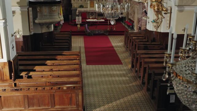 Couple walking through a church, genuflecting before entering a pew, and sitting together to pray in a quiet space, high-angle rear view.