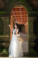 Obraz premium Portrait Fashion Asian Woman in White Gown at Ancient Brick Temple Architecture in Chiang Mai Thailand