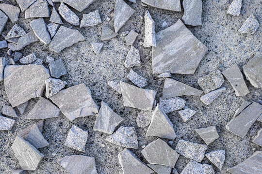 Cracked and broken cement texture with rubble fragments. A distressed surface pattern featuring scattered stone pieces, perfect for creative backgrounds, graphic design overlays, or architectural.
