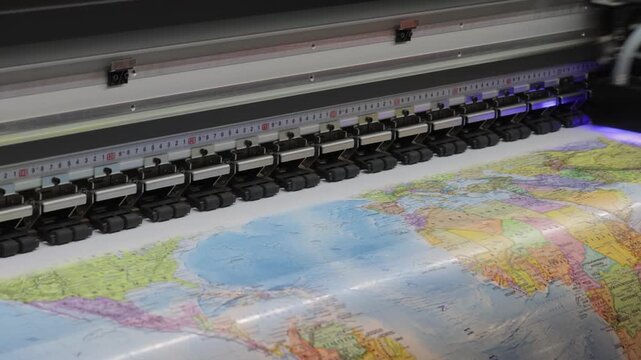 Large format printer creates detailed world map on vinyl material with ultraviolet curing.