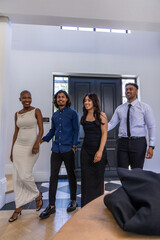 Diverse friends walking through bright entry toward camera, wearing formal attire by dark doors © wavebreak3