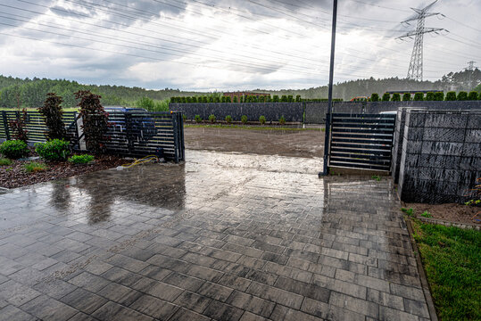 Heavy rain falling on a suburban driveway pavement