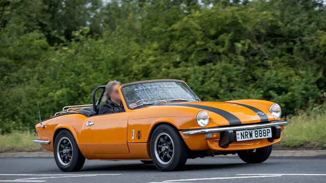 Stony Stratford,Bucks,UK - June 7th 2026: 1976 orange Triumph Spitfire classic car driving on a British road