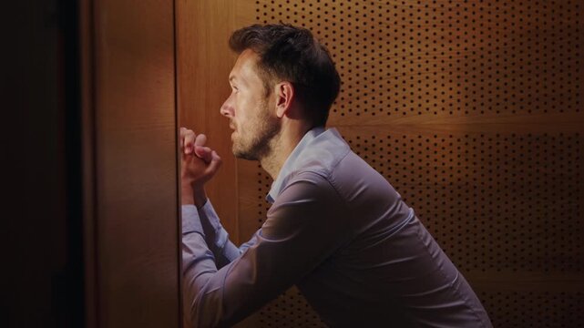 Man penitent, in a confession booth, confessing sins to a priest to receive absolution and spiritual healing. Faith concept.