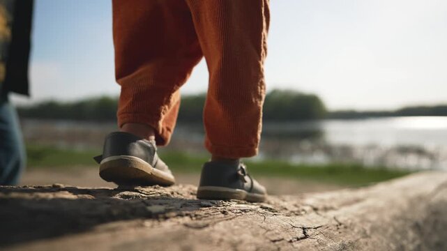 Toddler takes step outside father. Father supports toddler first step. Toddler outside with father. Outdoor exploration family step. Father helps toddler navigate step outside. happy family concept.