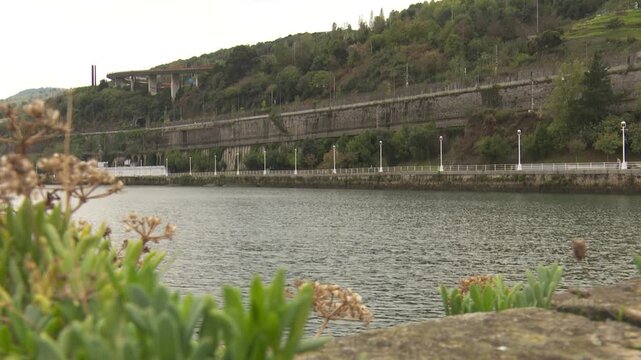 Scenic nervion river flowing through bilbao with green hill landscape