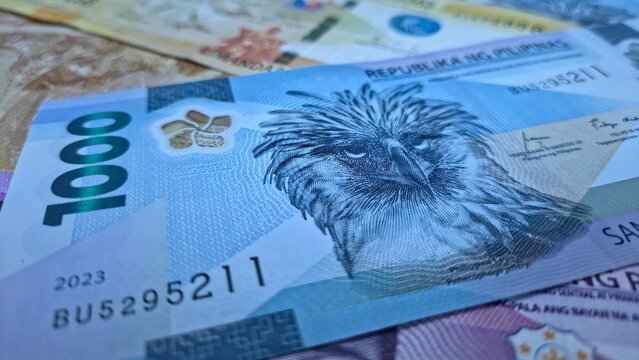 Close-up of a blue 1,000 Philippine peso or piso banknote with other denominations blurred in the background. Vibrant currency texture and detail, ideal as a financial or money-themed background.