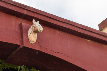 Antique Horse Head Sculpture Mounted on Red Building Beam, Architectural Detail and Ornament © Noel