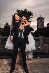 Fototapeta premium Happy mixed race wedding couple piggybacking outdoors