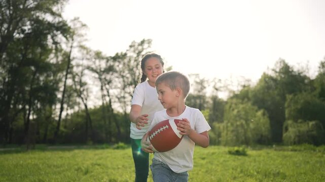 Child running with ball in park. Young boy runs throws football. Family fun outdoor activity child play catch. Kid joyfully runs active playtime. Child game of catch running joyfully with ball.