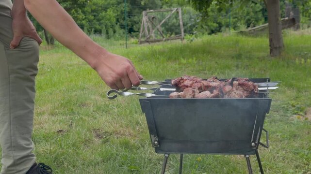 Person cooking pork shish kebab on skewers