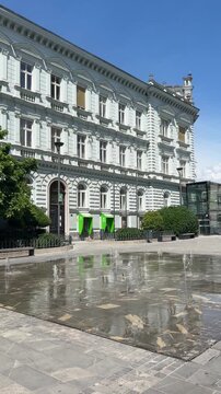 Real-time POV video of a beautiful water fountain spraying in front of a historic building and architecture in Celje, Slovenia