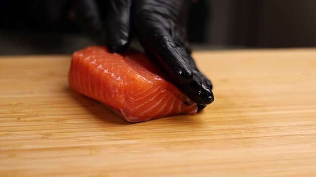 Close-up of a chef slicing fresh salmon on a wooden cutting board. Sharp knife, detailed texture of raw fish, and professional kitchen atmosphere emphasize precision, freshness, and gourmet culinary p