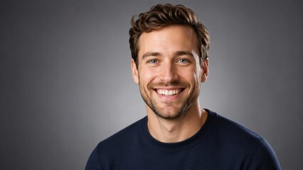 Obraz premium Smiling young man wearing navy sweater in gray studio portrait