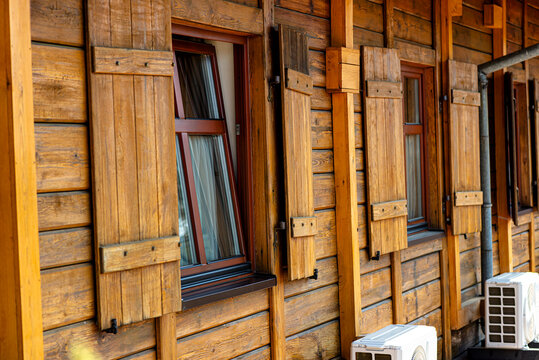 Wooden house facade featuring windows with shutters and air conditioning units