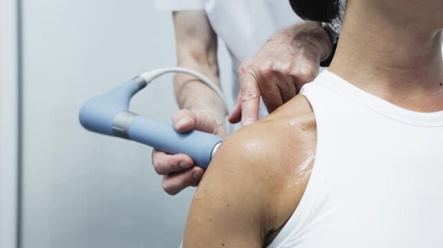 Female patient undergoing shockwave therapy in a modern clinical setting. Concept rehabilitation, pain management and physical therapy.
