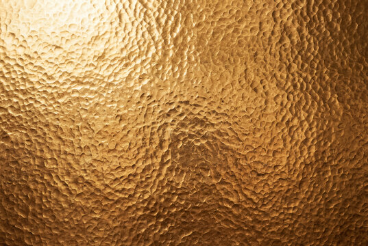 High angle close up textured surface of rich hammered deep gold background