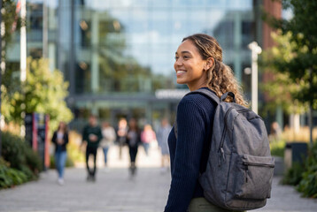 Fototapeta premium Smiling female student with backpack walking on university campus