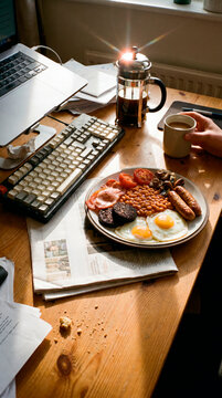 Hearty full English fry up breakfast beside vintage keyboard at office desk