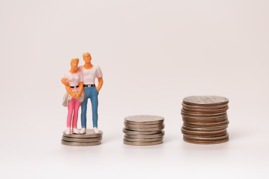 積み重ねたお金と寄り添う男女のカップルのミニチュ資産形成 人生設計 夫婦のお金イメージ
