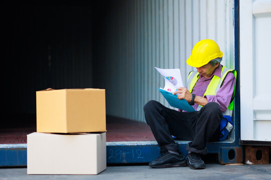 Elderly asian Senior dock worker working at Cargo container yard. Inspec stock product in container box. cargo shipping container box in logistic shipping yard