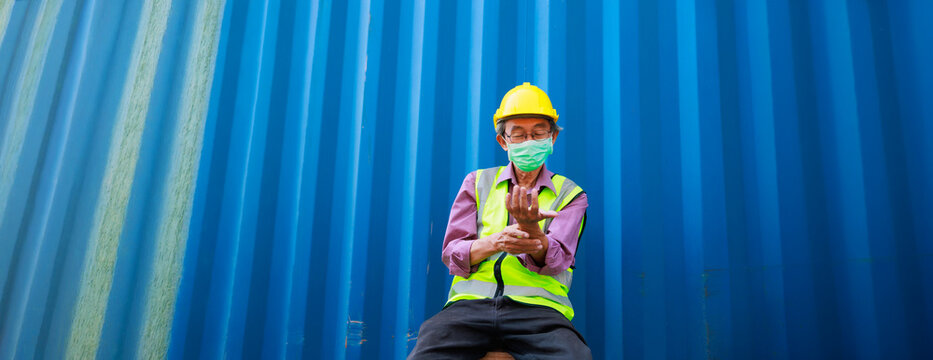 people holding hand painful inflammation, wrist tendonitis. Tired asian senior male container worker in protective face mask, hardhat helmet and uniform