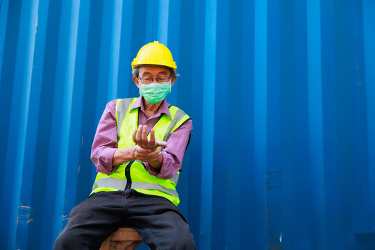 people holding hand painful inflammation, wrist tendonitis. Tired asian senior male container worker in protective face mask, hardhat helmet and uniform