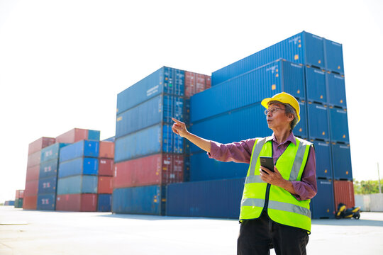 Senior dock worker working and use smartphone at Cargo container yard. Marine and carrier insurance concept. cargo shipping container box in logistic shipping yard