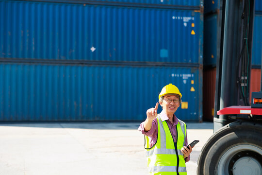 Senior dock worker working and use smartphone at Cargo container yard. Marine and carrier insurance concept. cargo shipping container box in logistic shipping yard