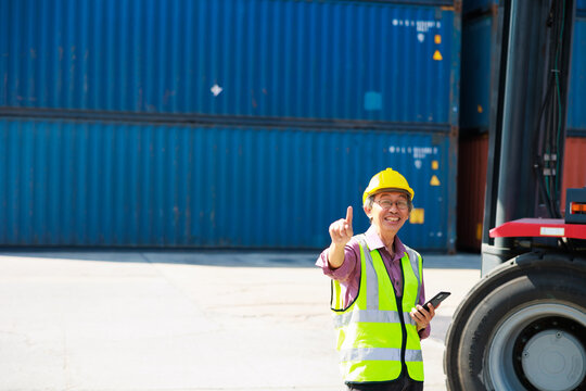 Senior dock worker working and use smartphone at Cargo container yard. Marine and carrier insurance concept. cargo shipping container box in logistic shipping yard