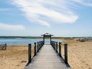 Obraz premium Marennes-Plage in Charente-Maritime. Wooden jetty on a supervised sandy beach equipped with water sports facilities, leading to an artificial swimming pool surrounded by a line of dunes. 