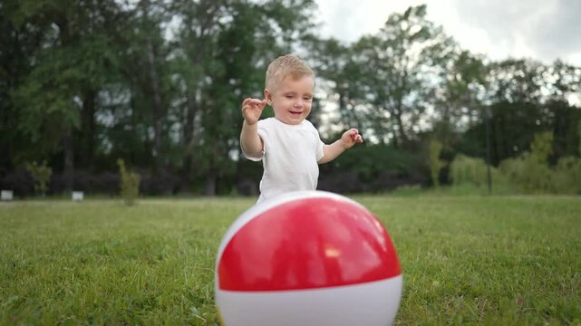 Toddler takes step with ball outdoors. Happy family moment park. Toddler playful exploration with ball. Family enjoying time outside. day in nature. Ball step family bonding. Ball step family outdoor.