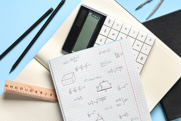 Naklejka premium Copybook with handwritten maths formulas and stationery on blue background