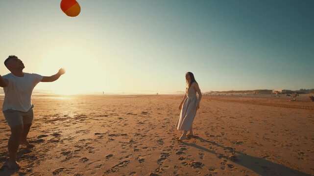 Friends play with a beach ball on a sunny day at the beach during the late afternoon