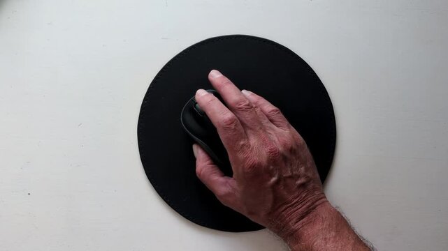 M&auml;nnliche Hand bedient Computermaus auf rundem Mauspad aus der Vogelperspektive