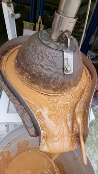A traditional stone mill crushes and kneads the mixture of almonds, honey and argan oil to make amlu, or amlou, a spreadable cream typical of Moroccan cuisine create with authentic artisanal technique