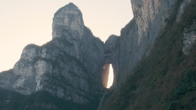 Heaven gate stone arch glowing at sunrise with steep staircase between towering cliffs at sunrise.in Tianmen Mountain National Park, Zhangjiajie, Hunan, China. Tianmen cave with 999 steps