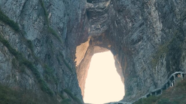 Natural stone arch with long staircase between towering cliffs at sunrise.in Tianmen Mountain National Forest Park, Zhangjiajie, Hunan, China. Tianmenshan cave with 999 steps